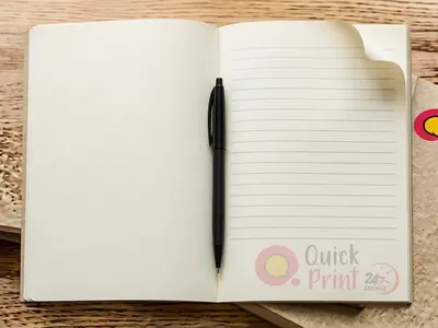Gum-bound A5 notepads with branded header on an oak desk, printed in Hyderabad