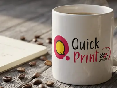 White ceramic mug with a printed logo on a wooden table beside a notebook and coffee beans, Hyderabad